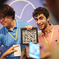 Two founders a their stands holding a QR code