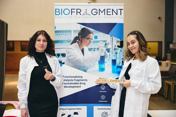 A photo of the two BioFragment co-founders standing by their company banner